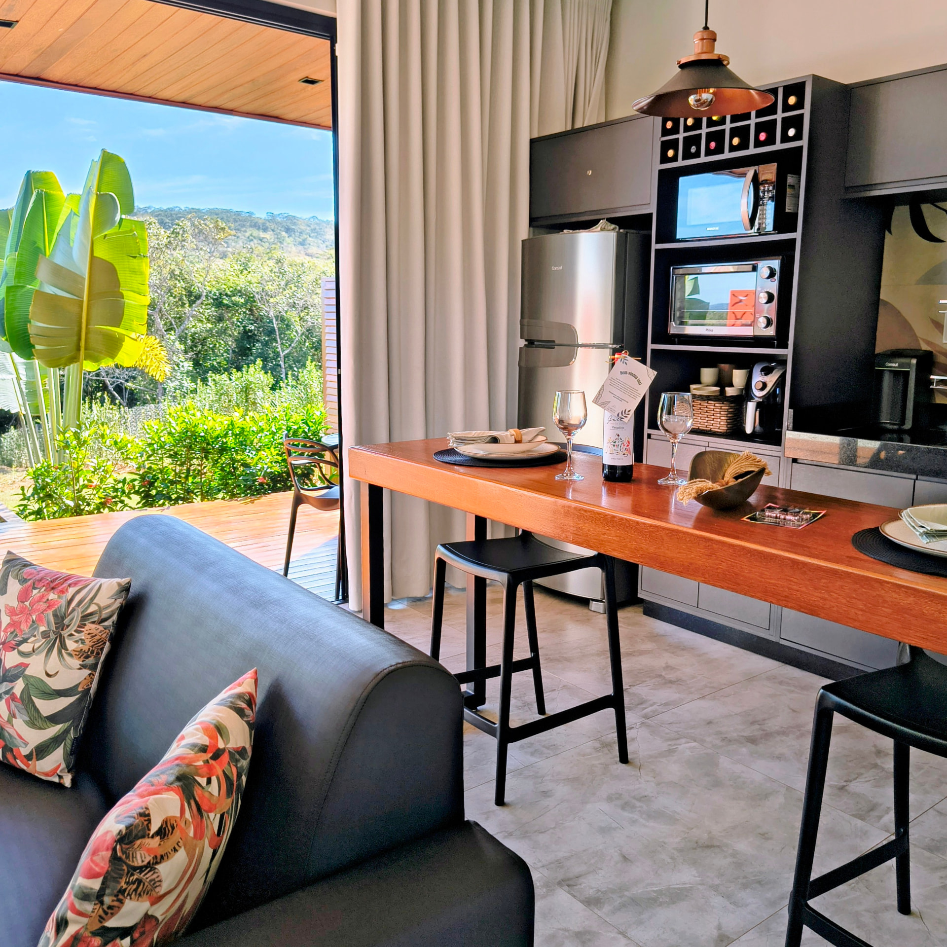 Cozinha completa equipada com bancada de madeira, eletrodomésticos e vista para a natureza