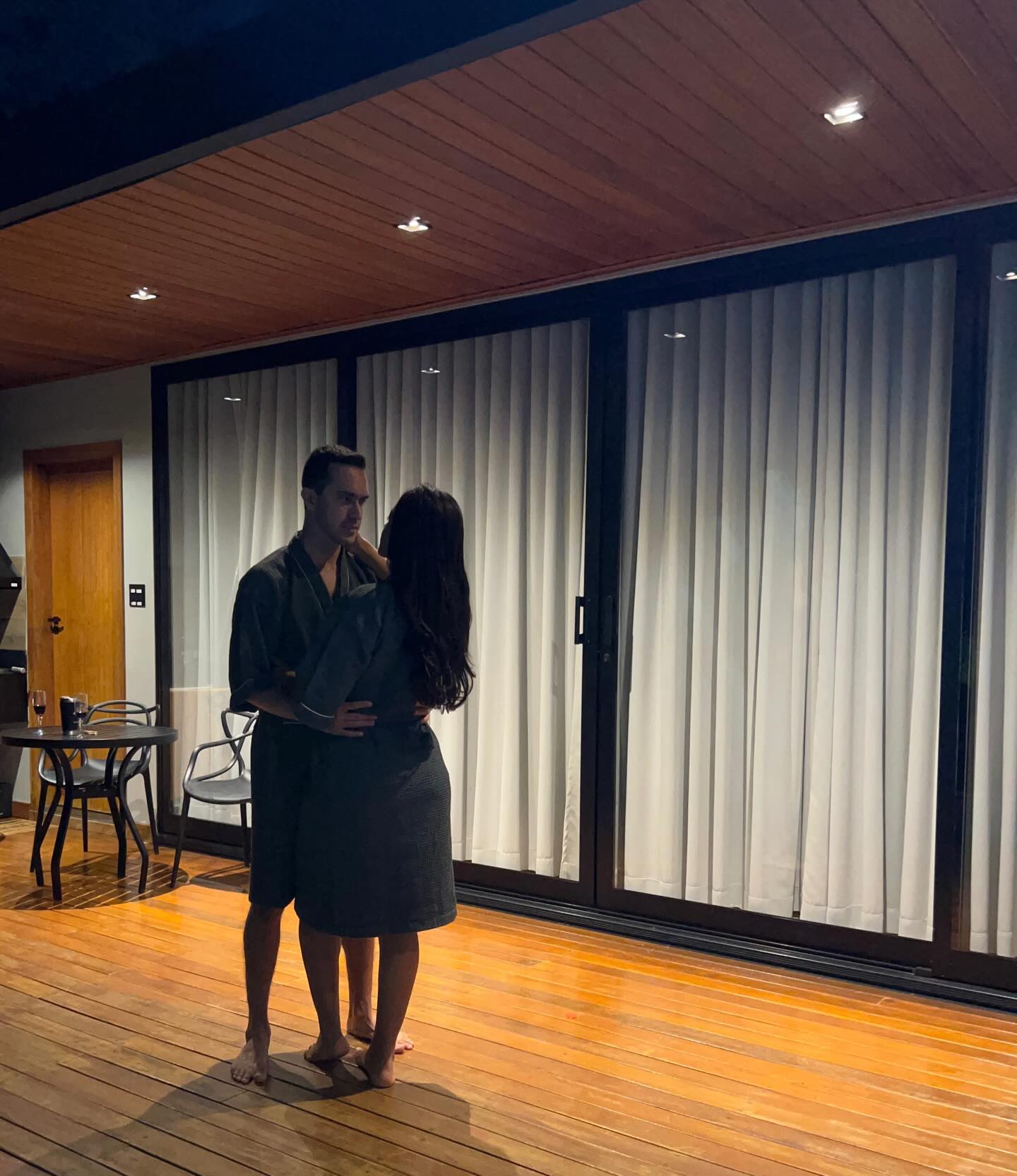 Casal de roupão abraçado na área externa do loft à noite