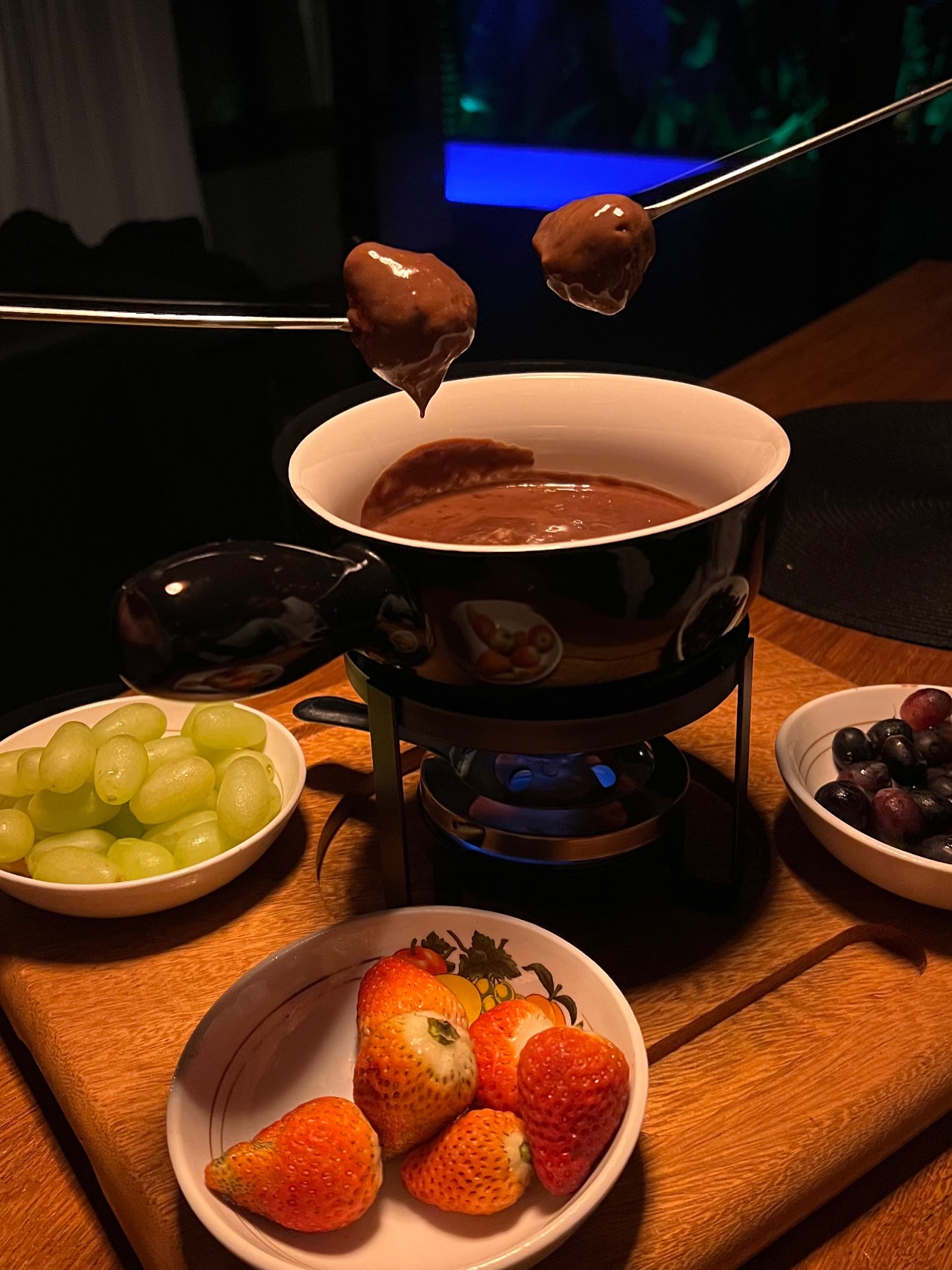 Fondue de chocolate com morangos e uvas à noite